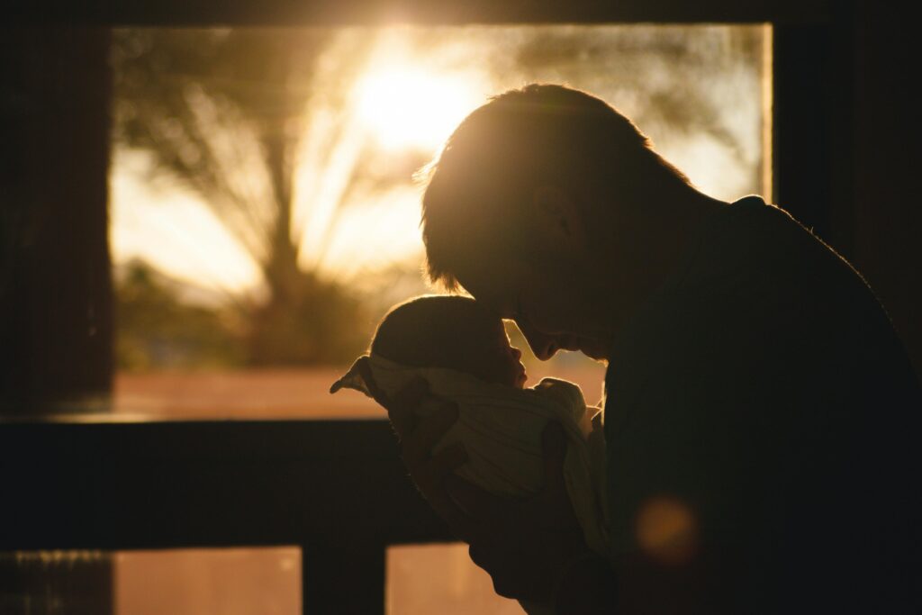 father holding his baby in sunset