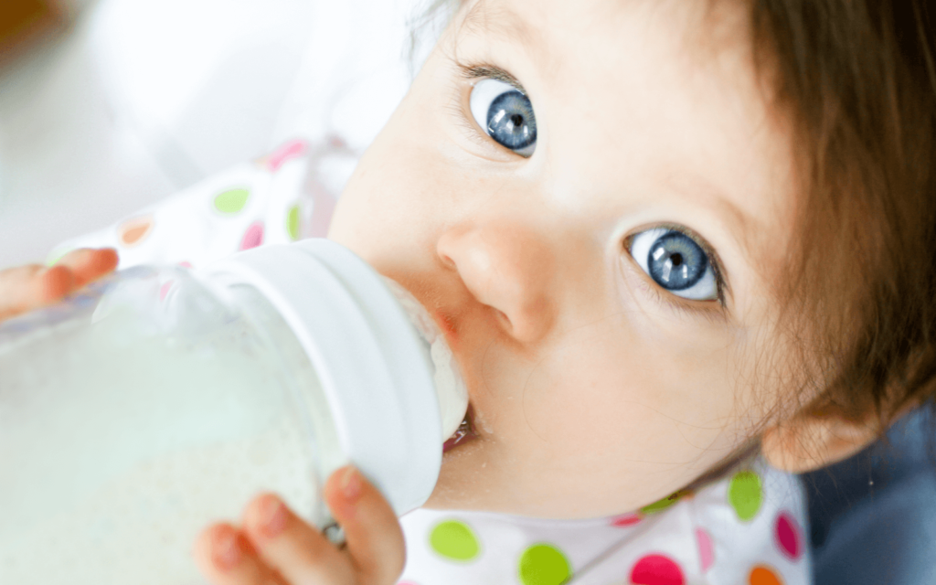 baby girl drinking from a glass baby bottle