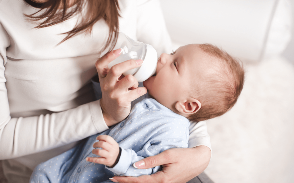 mom feeding her baby with a glass baby bottle