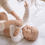 mom is dressung her baby with long-sleeved bodysuit