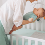 mom puting her baby to sleep in his crib