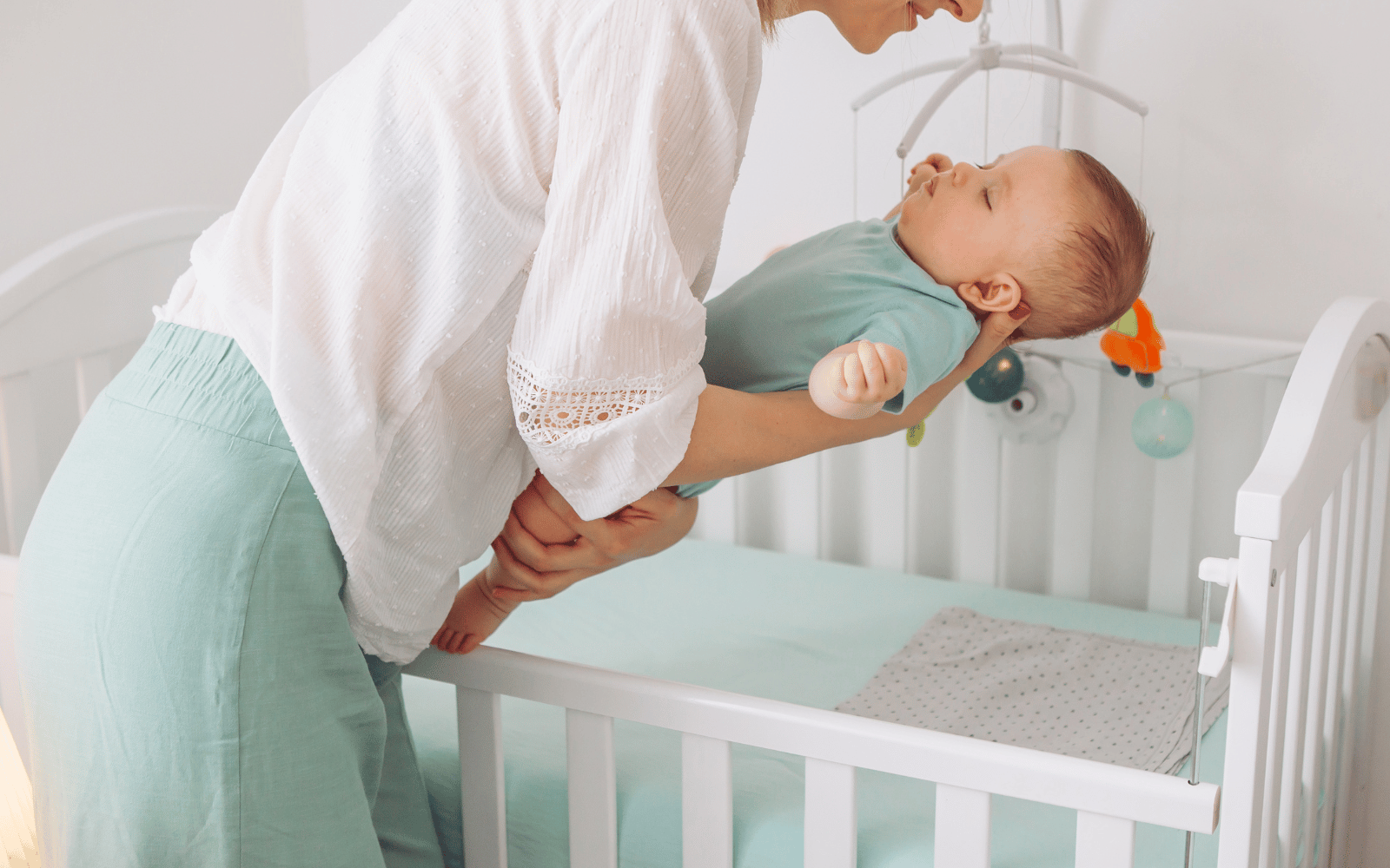 mom puting her baby to sleep in his crib