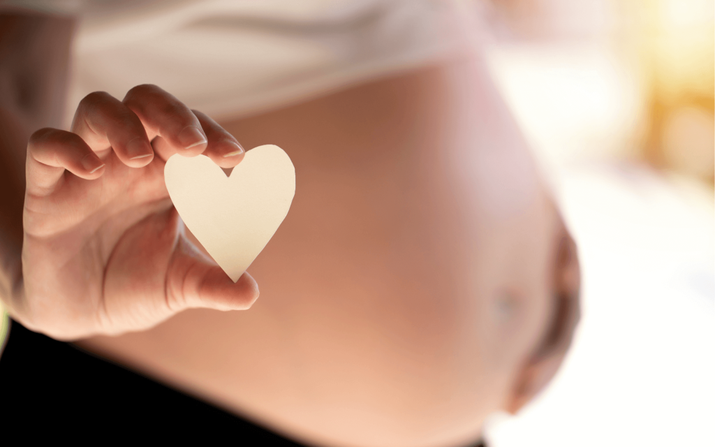 pregnant woman holding a heart shaped paper