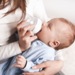 Mom feeding her baby with glass baby bottle