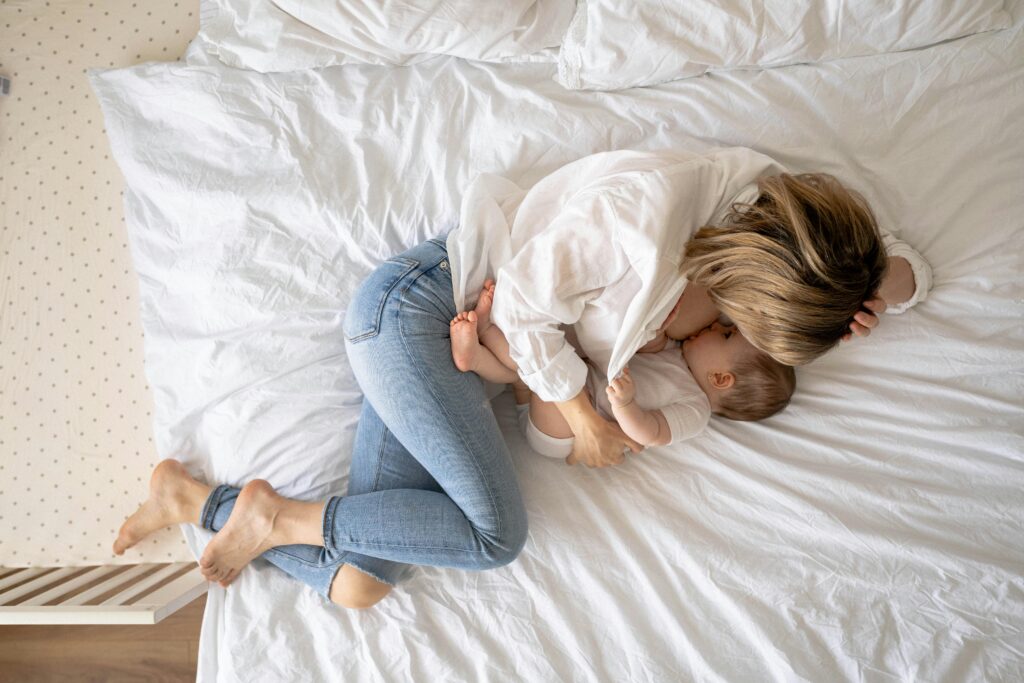 mom breastfeeding her baby lying on a bed