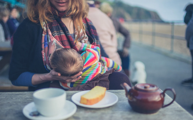 A Mom breastfeeding her baby in a coffee shop in the cradle hold