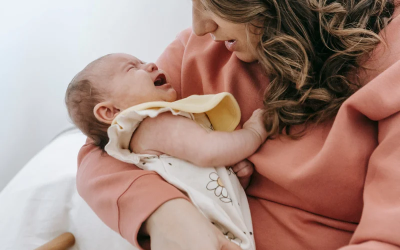 A Mom holding her crying baby that refuse to breastfeed