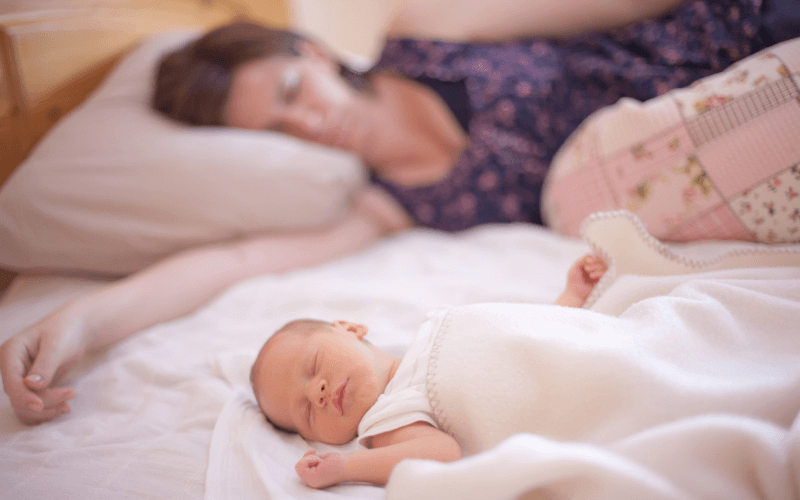 Mom sleeping while her baby is also sleeping