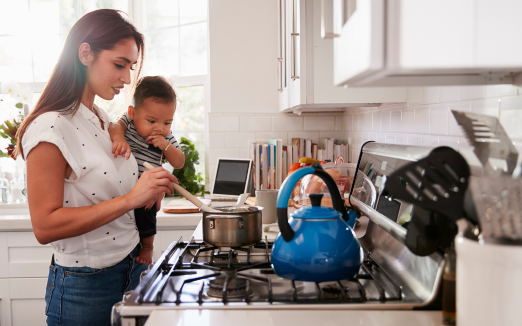 mom is holding her baby and cooking