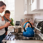 mom is holding her baby and cooking