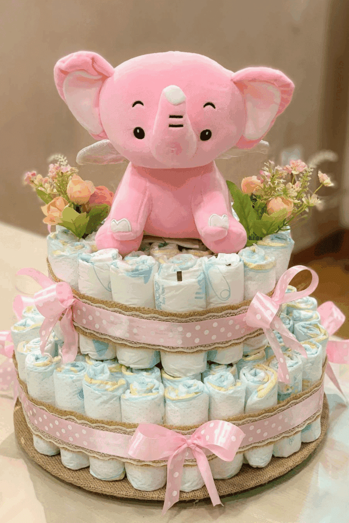 three-tiered diaper cake features a plush pink elephant topper